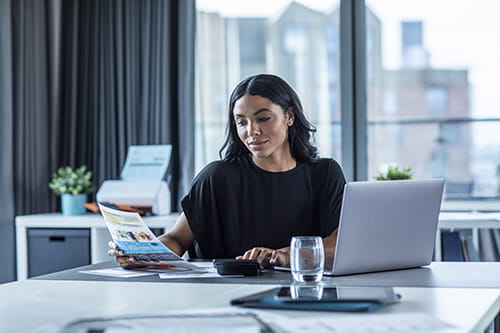 woman sitting in office with a printed paper on her hand